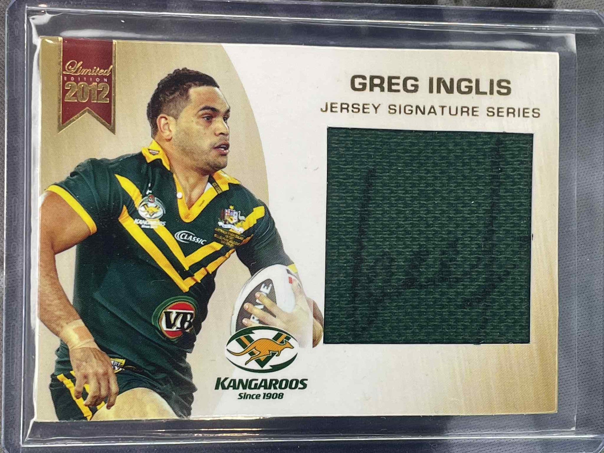 Trading card of Greg Inglis with a piece of jersey fabric, framed in clear plastic.